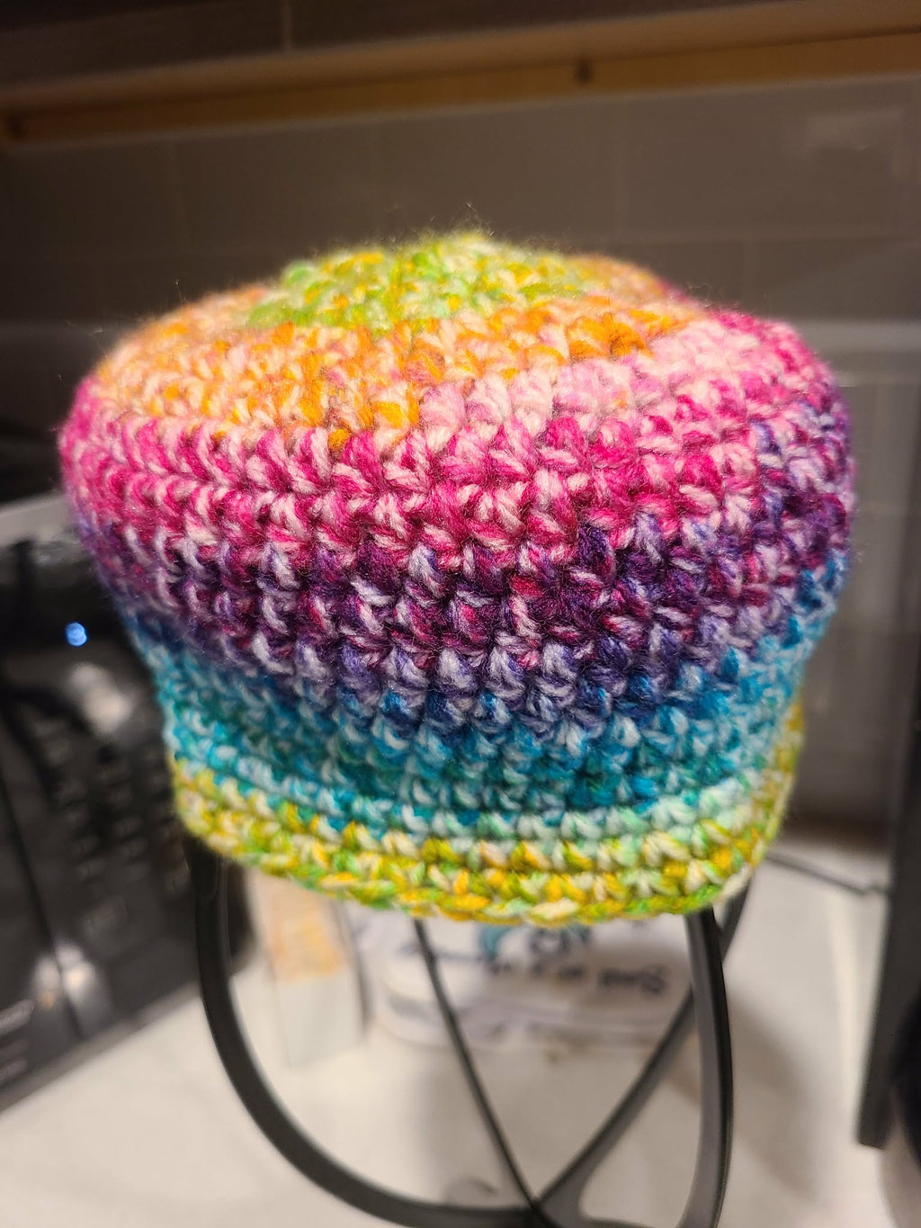 Side view of colorful crocheted baby beanie on a mannequin head 