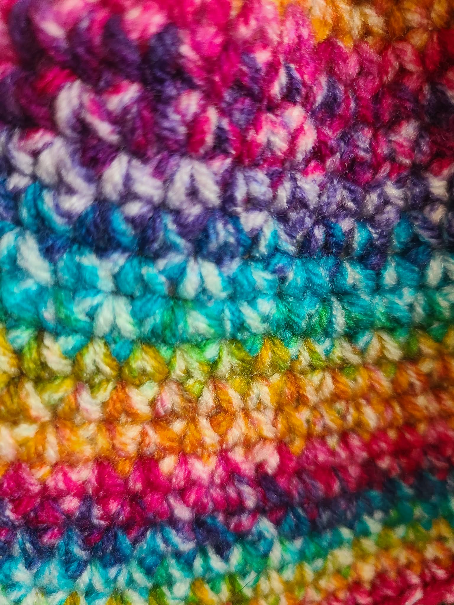 Close-up of colorful crocheted fabric with a rainbow pattern.
