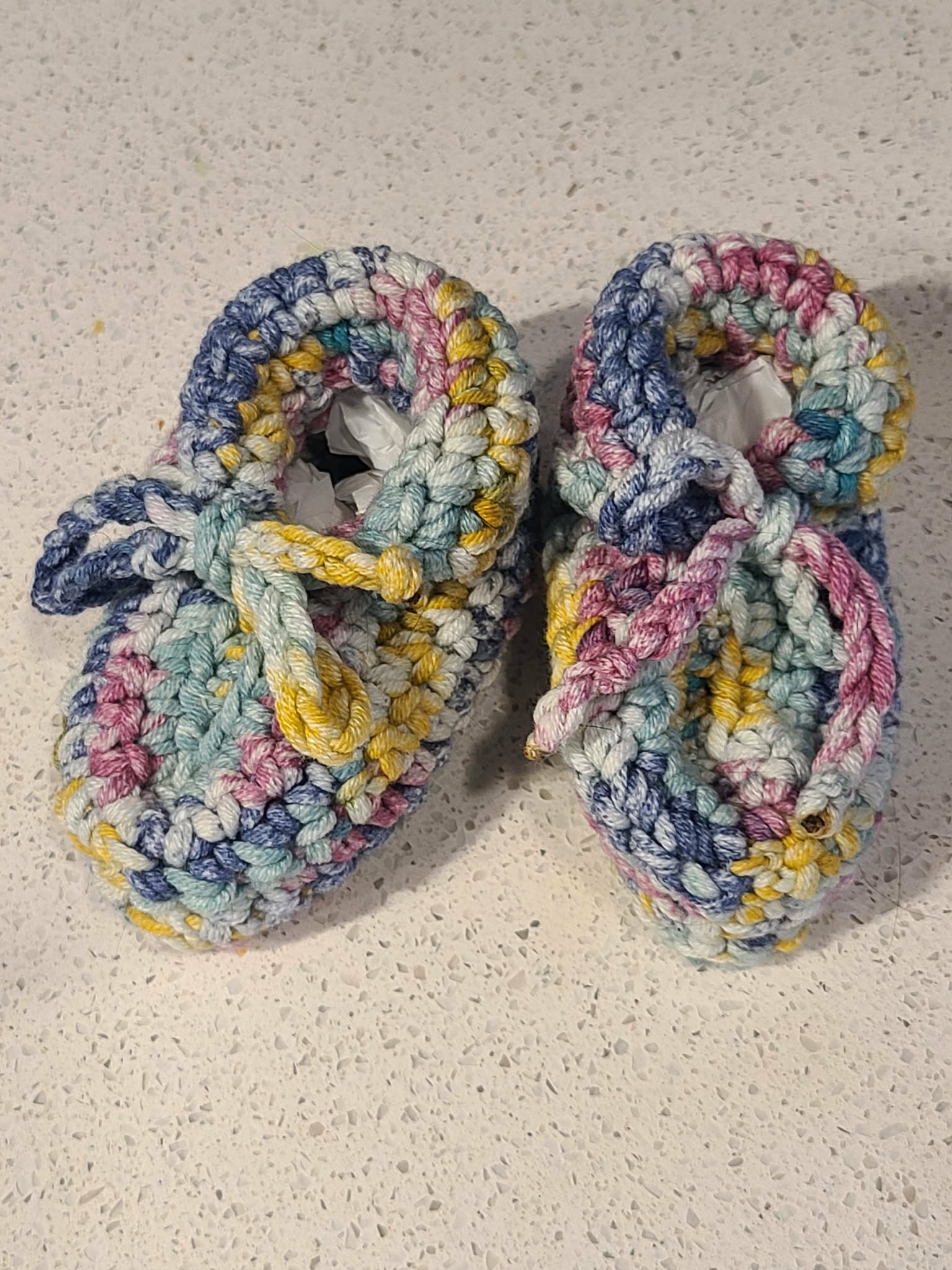 Pair of colorful crocheted slippers on a textured surface
