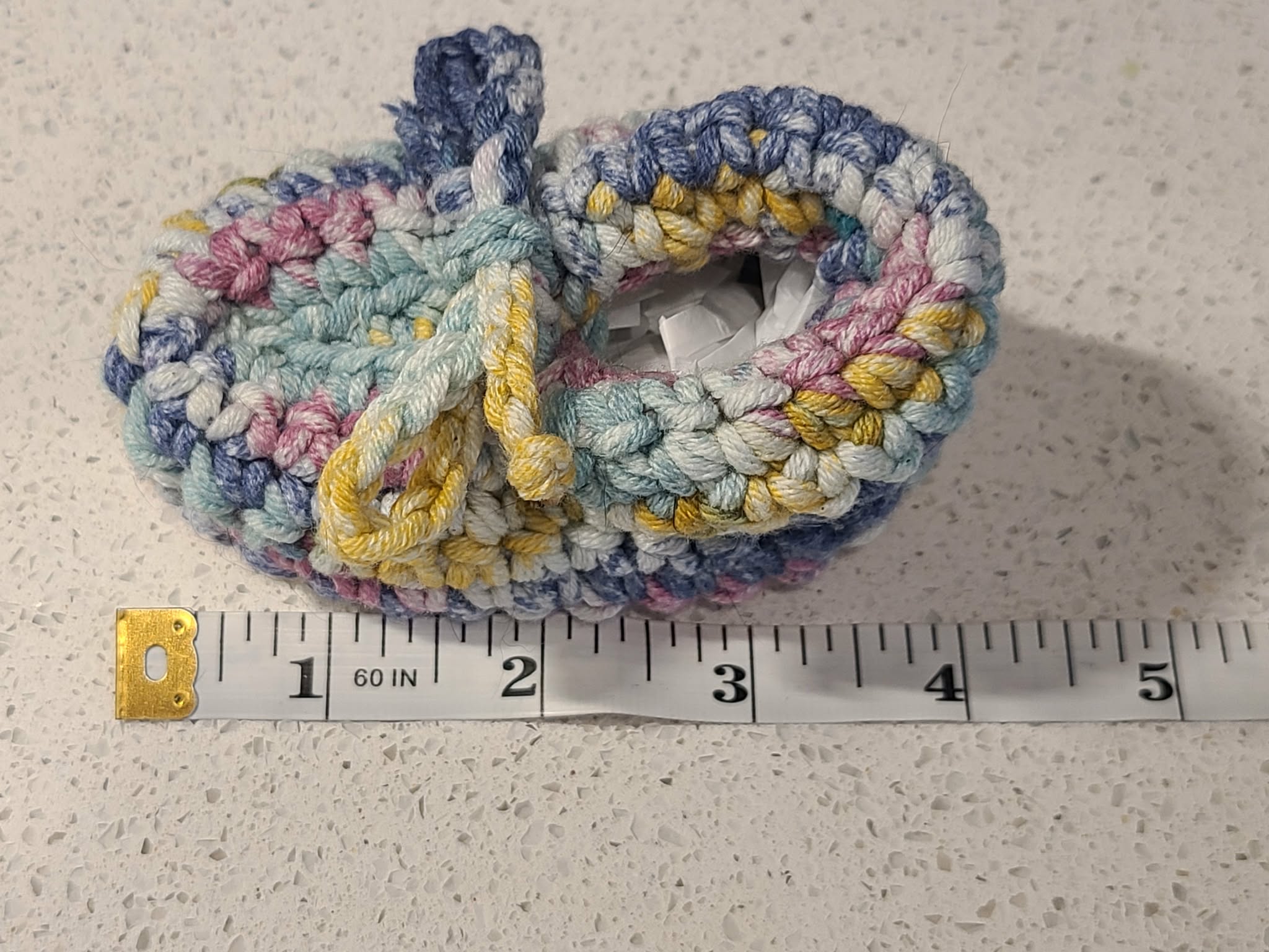 Colorful crocheted bootie top view with a ruler for scale 